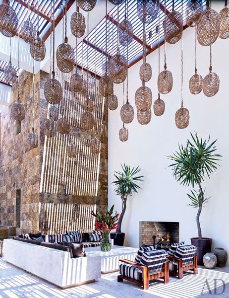 Clooney's courtyard: Twine-wrapped lanterns are suspended from the slatted canopy over Clooney’s courtyard, which features a Legorreta-designed cement-plaster table and L-shaped sofa, the latter topped with cushions in a Holly Hunt fabric and vintage pillows from John Robshaw; the armchairs are by Ralph Lauren Home.